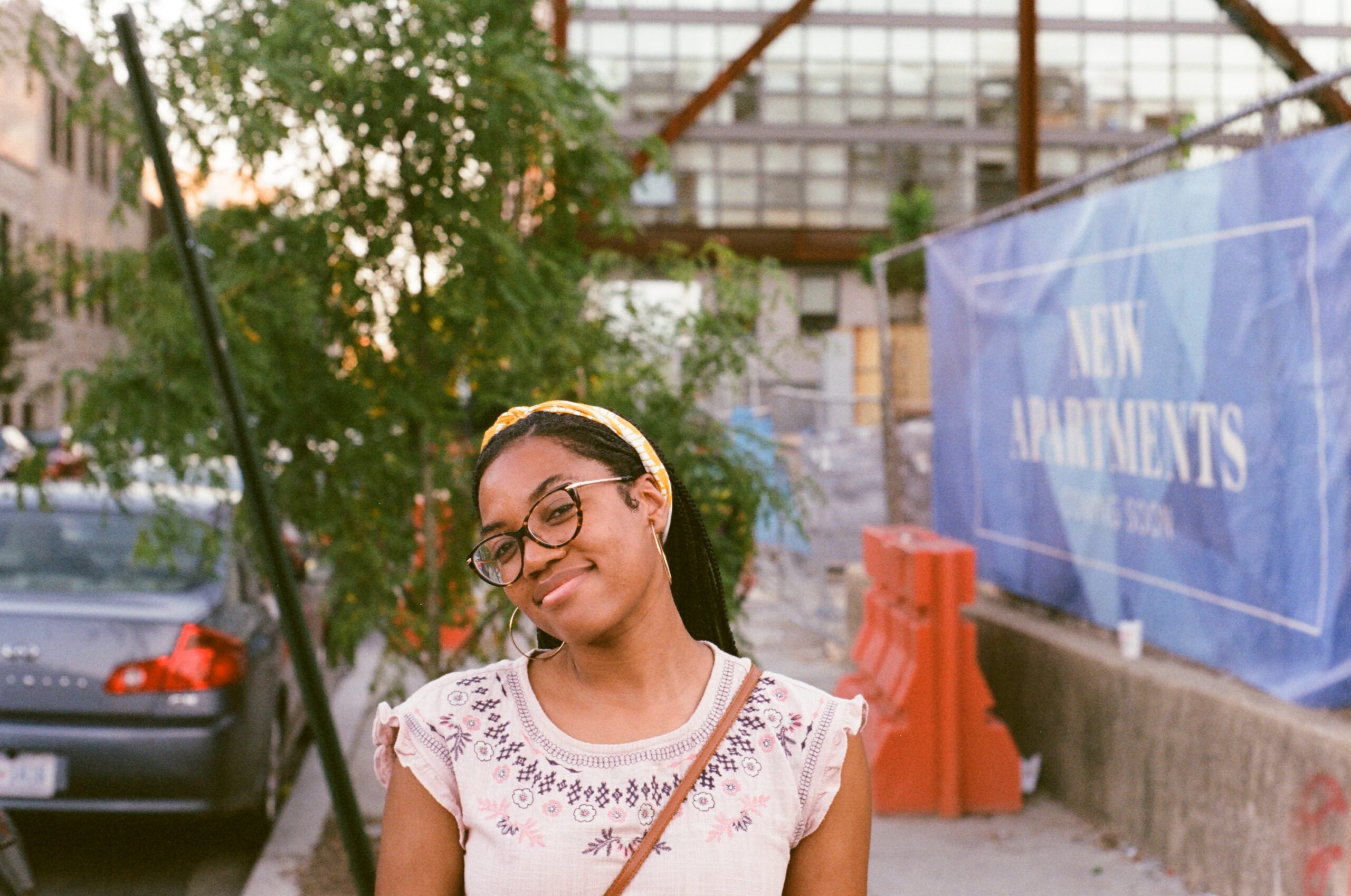 A woman smiles next to a sign that says "New Apartments Coming Soon"