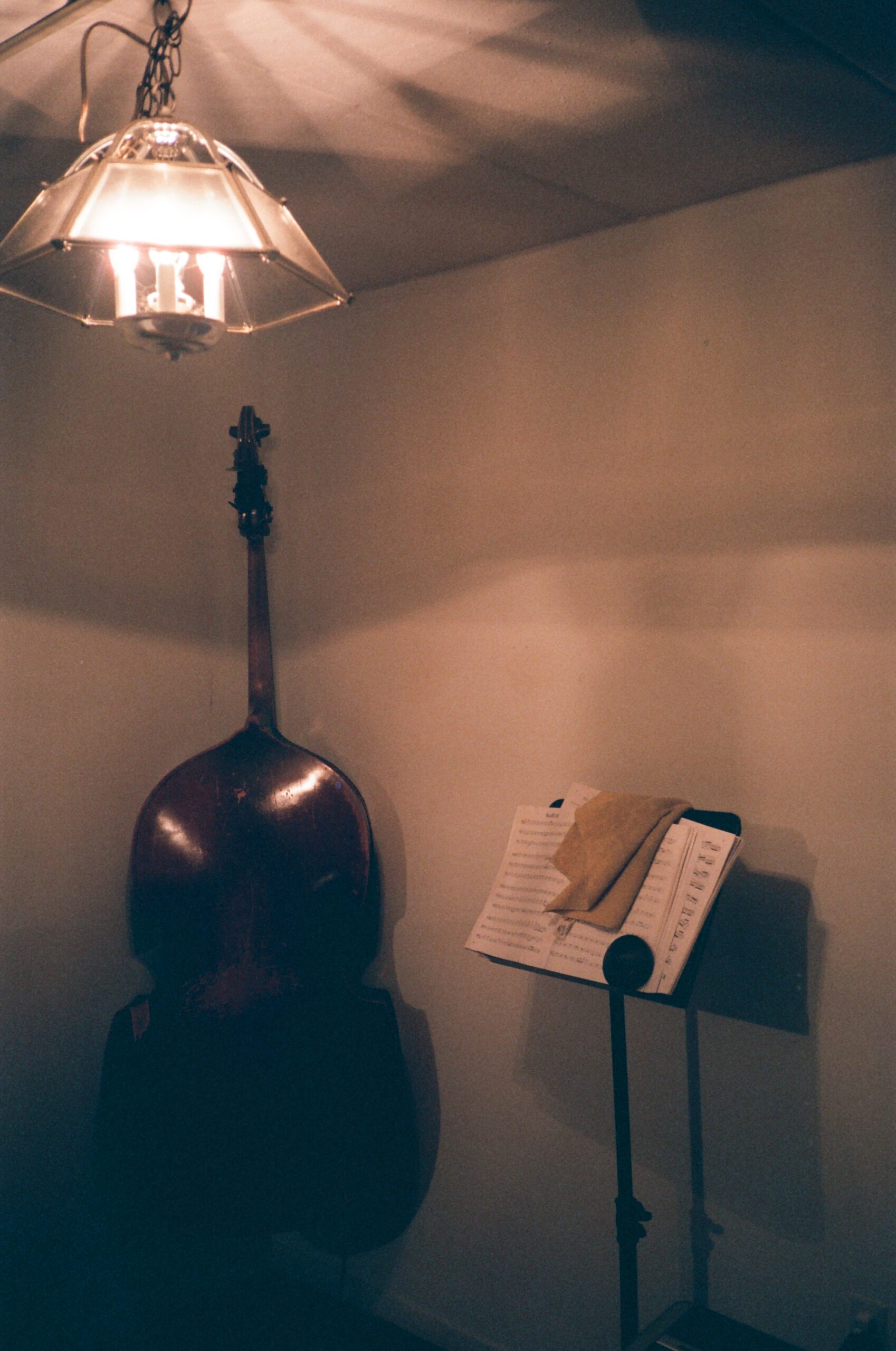 double bass leans against a white wall next to a music stand