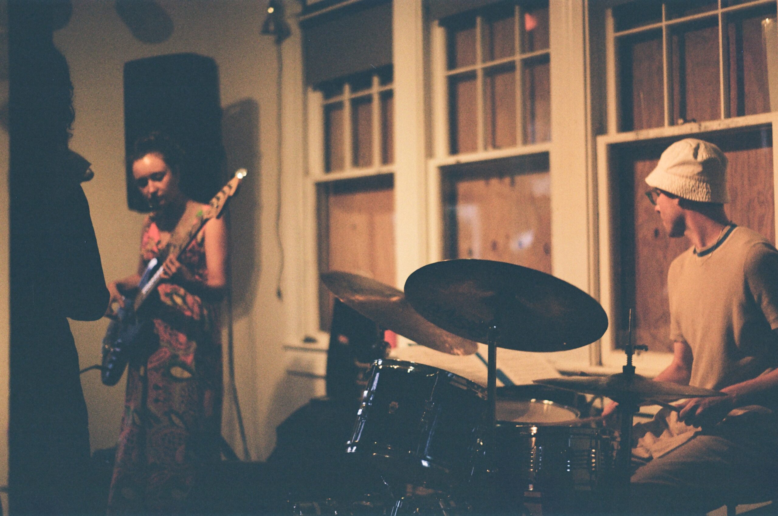 A drummer and guitarist play in front of three boarded up windows